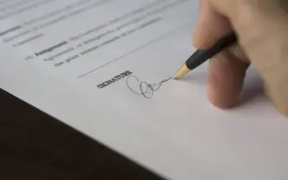 A hand signing an official document with a fountain pen